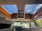 Interior of an RV rental van showing ceiling skylights, a vintage TV, and polished wood trim. Perfect for travel.