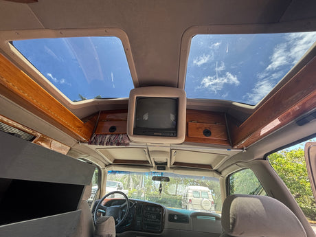 Interior of an RV rental van showing ceiling skylights, a vintage TV, and polished wood trim. Perfect for travel.