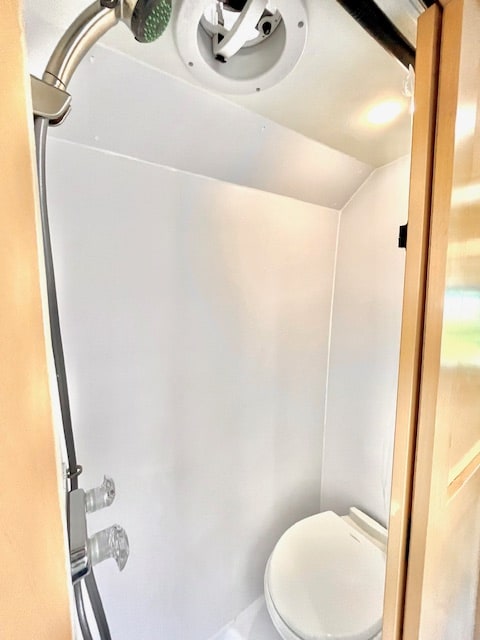 Clean, compact RV rental wet bath with shower, toilet, and ceiling fan. Essential amenities for comfortable travel.