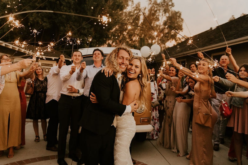 A joyful couple embraces amidst sparkling send-off by cheering guests, a vintage RV rental enhancing their wedding celebration. — photo 19