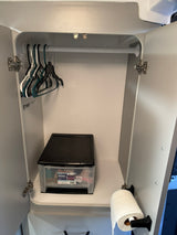 RV rental: A compact wardrobe featuring clothes hangers, a clear storage drawer, and paper towels for practical use.