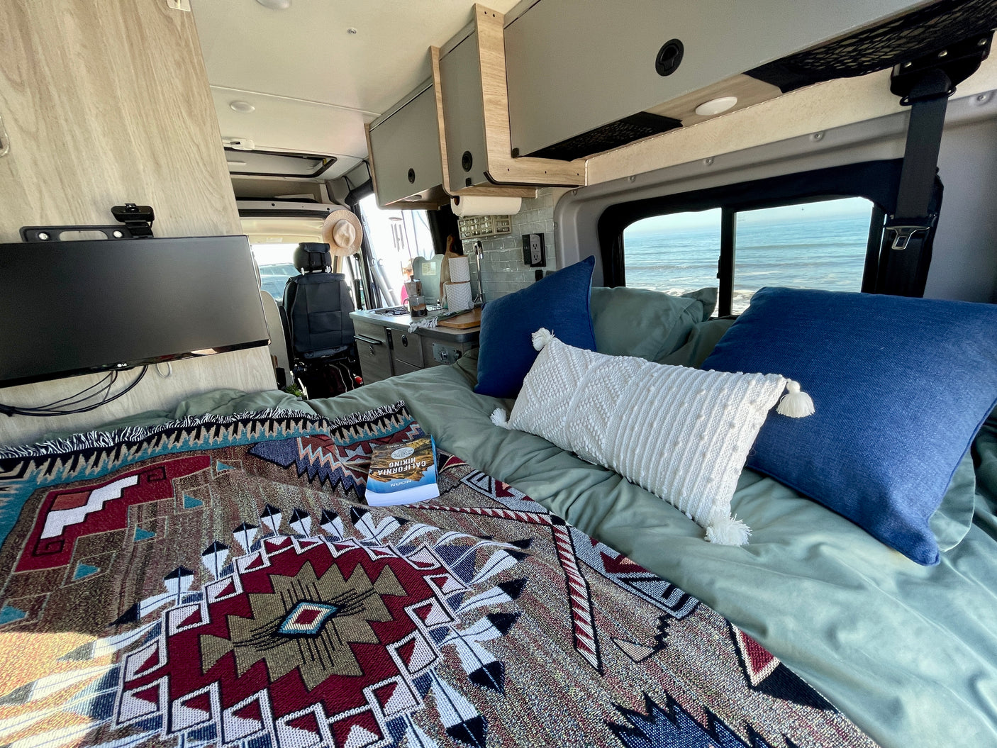 Cozy RV rental interior with bed, kitchen, and ocean views. Perfect for your next travel adventure!