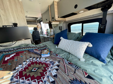 Cozy RV rental interior with bed, kitchen, and ocean views. Perfect for your next travel adventure!