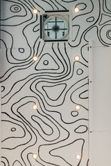 RV rental interior ceiling with unique black and white topographic map design, integrated lights, and a central fan.