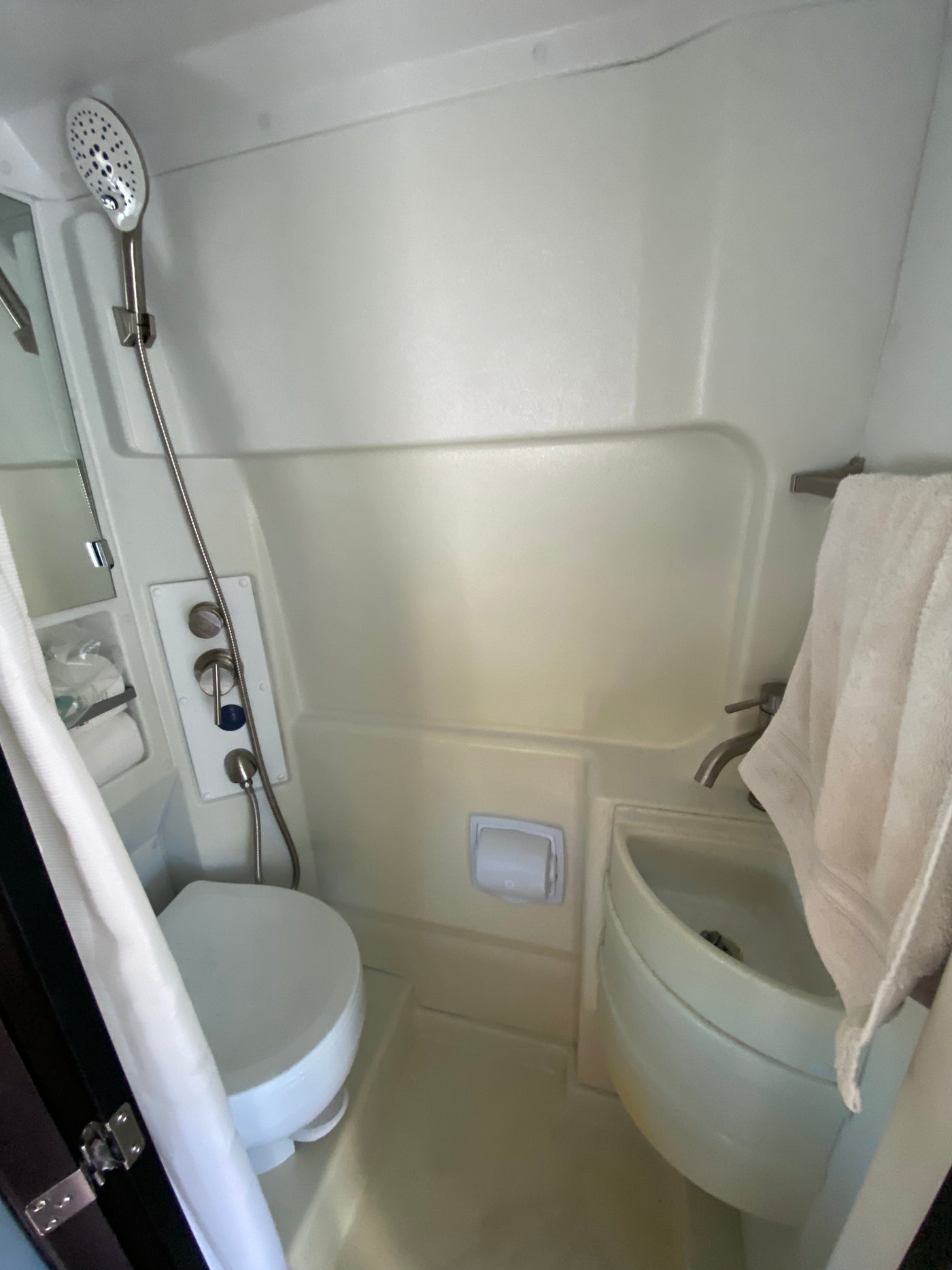 RV rental compact wet bath: shower, toilet, sink, and towel. Functional design for travel. — photo 10