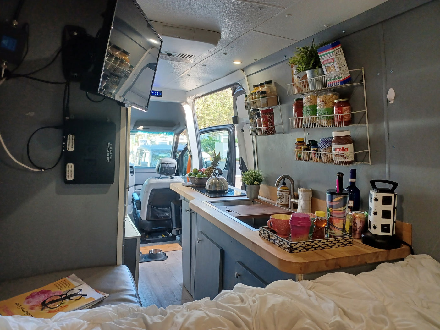 Cozy RV rental interior featuring a compact kitchen, comfortable bed, and entertainment setup, ideal for van life adventures. — photo 10