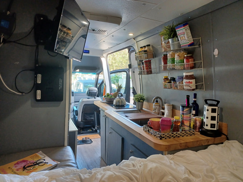 Cozy RV rental interior featuring a compact kitchen, comfortable bed, and entertainment setup, ideal for van life adventures. — photo 10