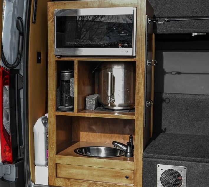 RV rental camper van kitchen featuring a microwave, Keurig, water dispenser, and sink in a wooden cabinet. — photo 18