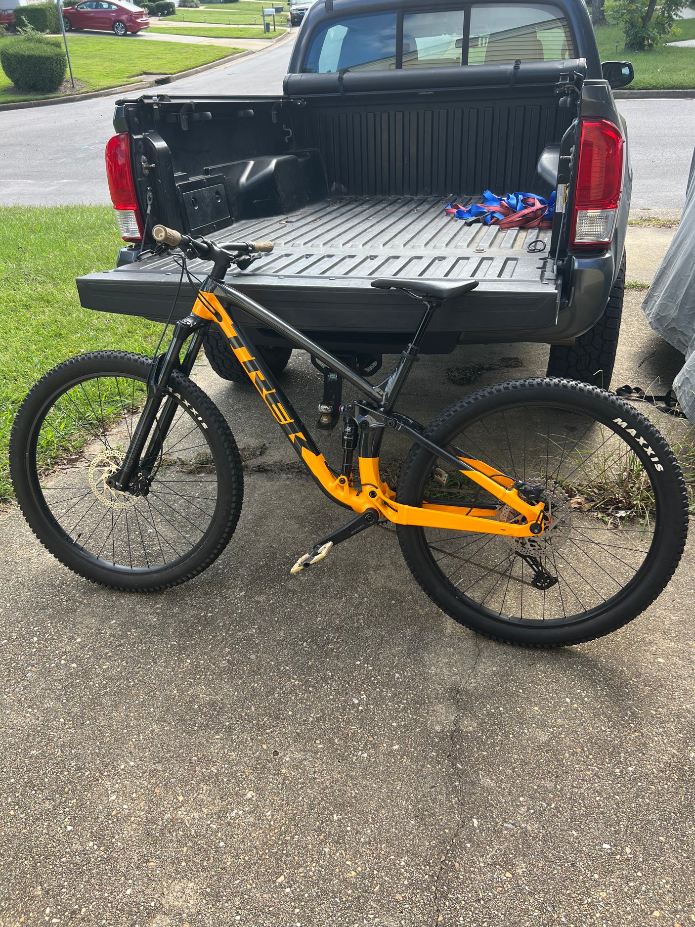 An orange/black mountain bike rests next to a pickup truck. Ideal transport for outdoor adventures, perfect alongside an RV rental trip.