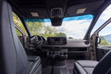 Inside an RV rental, the van's modern dashboard, steering wheel, and front seats with a clear view ahead.