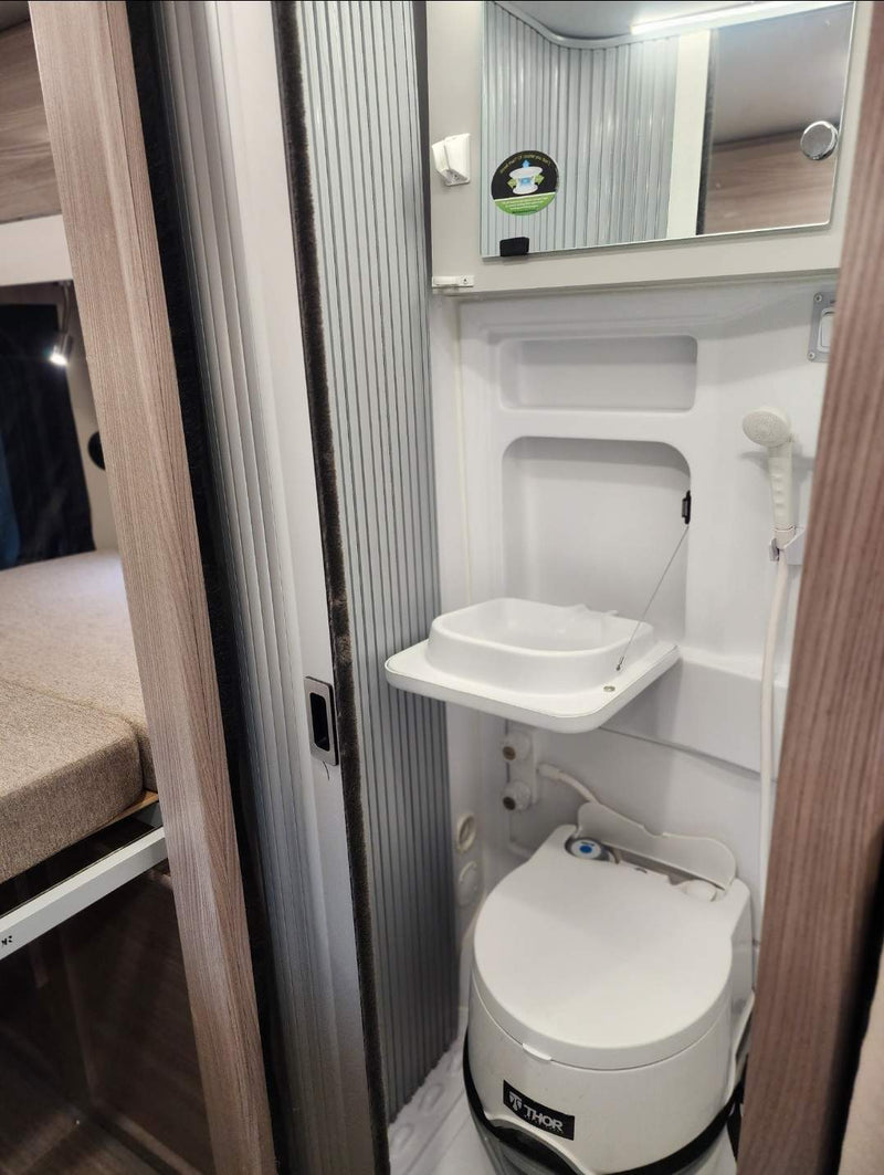  parked on a snowy road amidst trees. Ideal for an rv rental trip.|Dark gray Ram ProMaster camper van with pop-top (1 skylight — photo 5