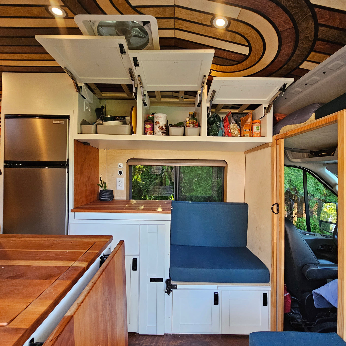 RV rental interior: cozy camper van with kitchenette, seating, and custom wood ceiling.