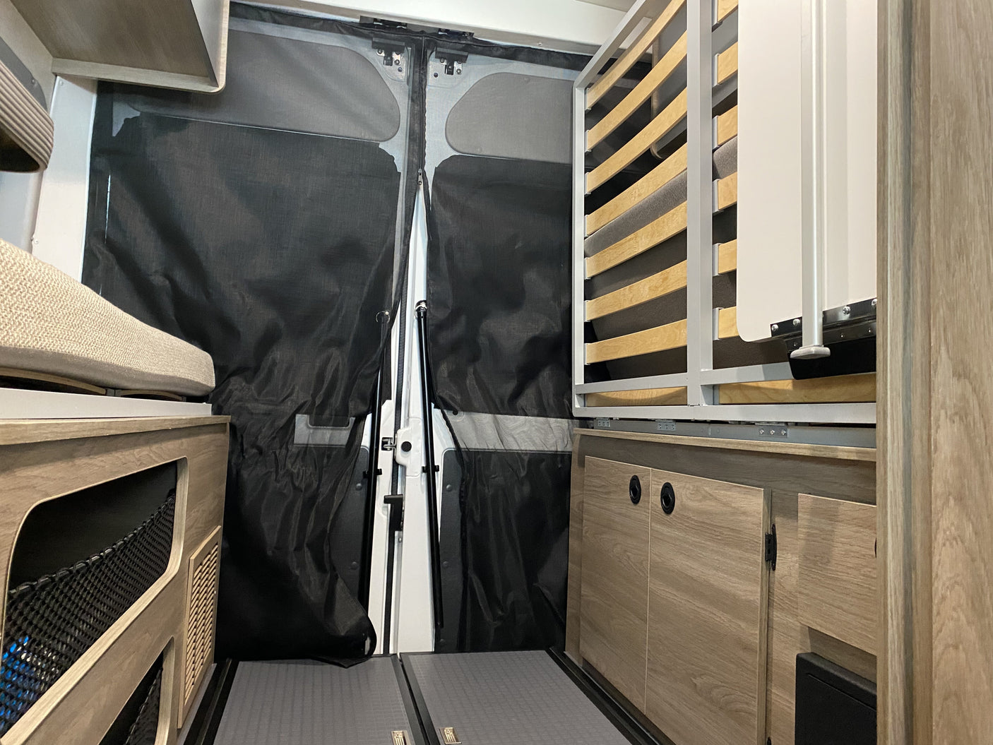 Inside a modern RV rental, featuring a foldable bed, rear mesh screens, and smart storage solutions for comfortable travel.