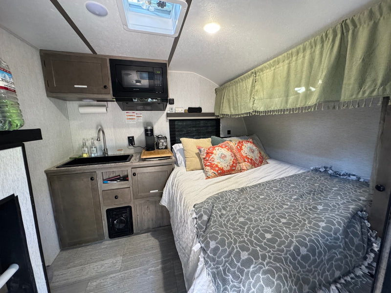  parked in a sunny lot.|Cozy RV rental interior featuring a compact kitchen with a sink — photo 5