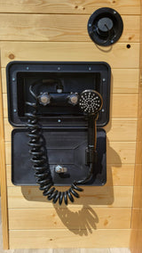 RV rental: Exterior hot/cold shower and water fill port on a wood-paneled wall, ready for outdoor use.