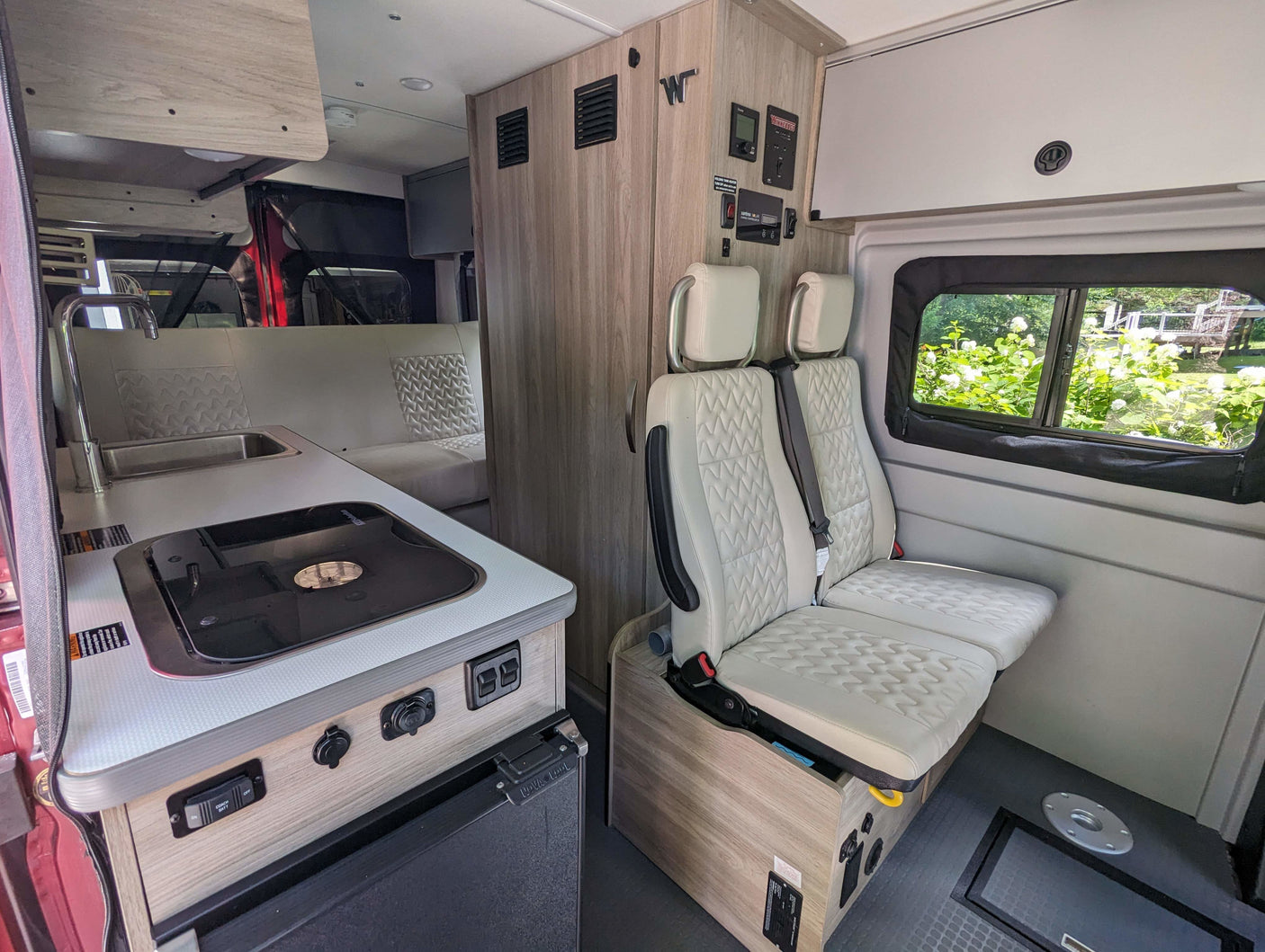 Winnebago RV rental interior: compact kitchen, comfortable passenger seats, and rear lounge area, ready for adventure.