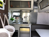 Experience RV rental comfort: a sleek, compact kitchen with dining area & built-in storage.