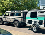 Ineos Grenadier SUV towing a Sunray Sport RV rental for camping trips. Ready for adventure on the road.