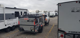 RV rental vehicles: A rugged ROG Survival Series trailer, a Wildwood RV, and others in a storage lot.