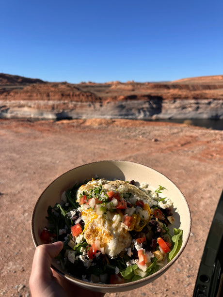 Enjoying a fresh breakfast bowl with eggs & veggies, overlooking a stunning desert lake during our rv rental adventure.