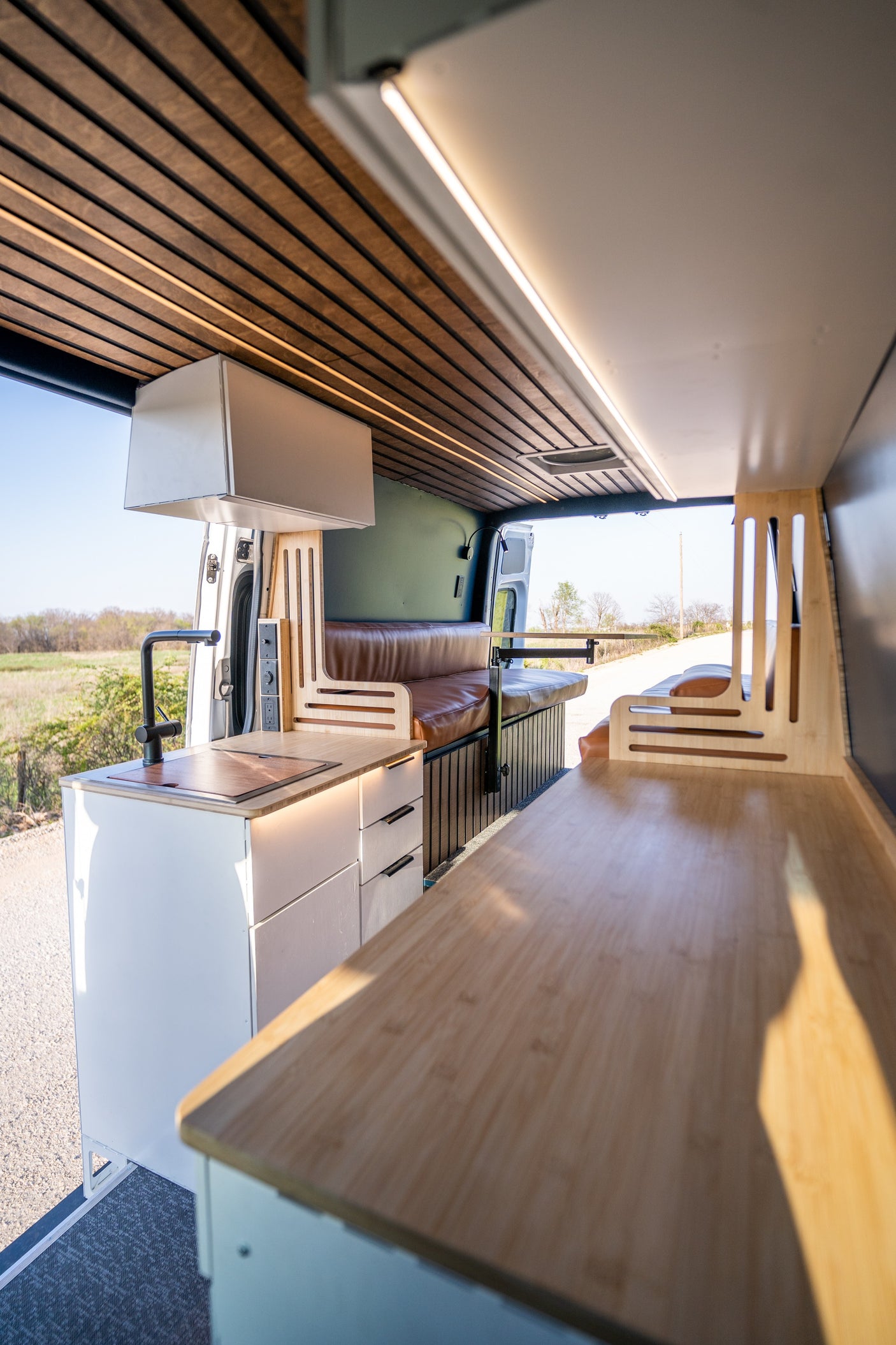 Modern camper van interior for rv rental, featuring a complete kitchen, cozy seating, and clever storage solutions.