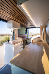 Modern camper van interior for rv rental, featuring a complete kitchen, cozy seating, and clever storage solutions.
