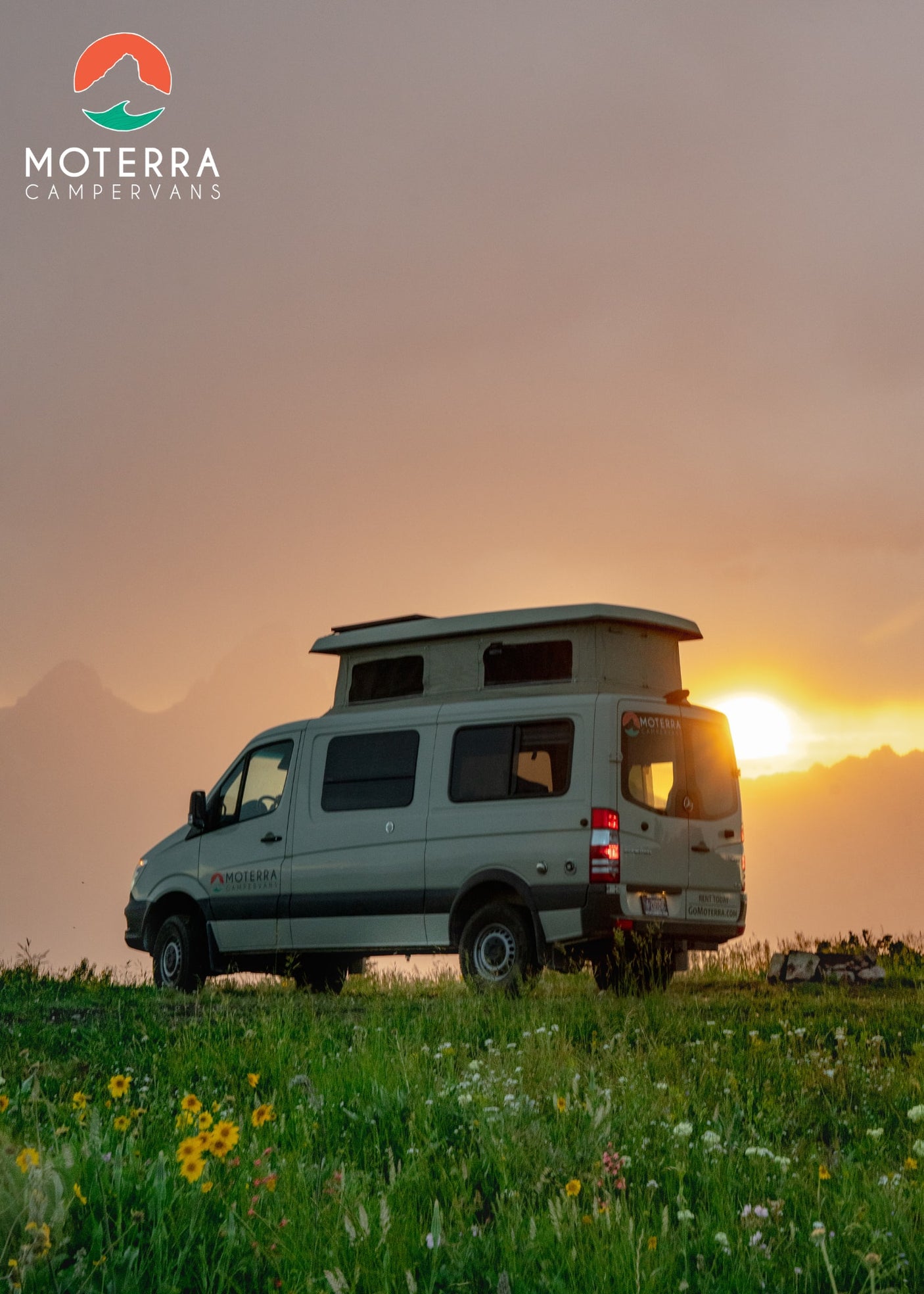 Gray camper van RV rental in a wildflower field at sunset, perfect for outdoor adventure.