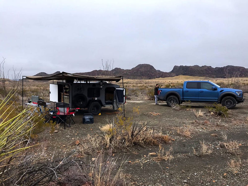  ideal for camping storage.|A sleek gray teardrop RV rental on a sandy beach. This compact off-road camper features a roof rack and front storage.|Outdoor cooking station for your RV rental: a red Everest stove — photo 2