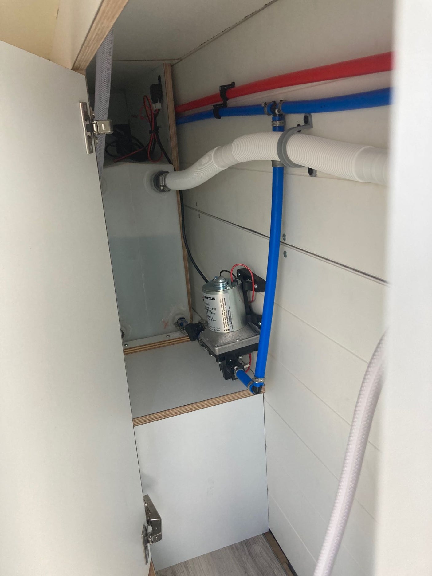Compact RV rental water system: showing pump, tank, and neatly routed PEX plumbing. Practical setup for adventurers.