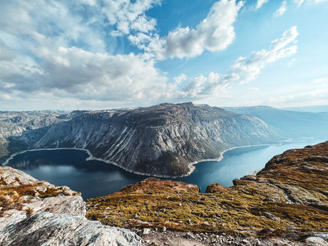 Panoramic vista of a deep blue fjord surrounded by towering mountains. Discover this natural wonder via an RV rental trip.