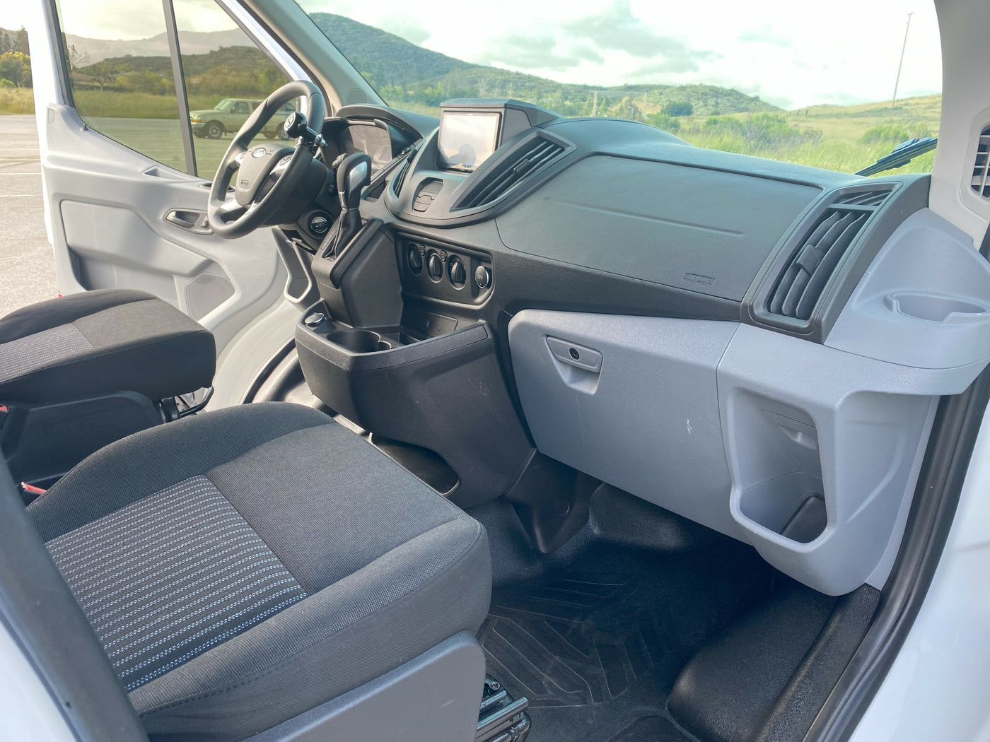 RV rental: View of a van's clean front cabin. Shows driver's controls, dashboard, and two front seats. — photo 9