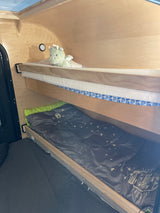 Cozy bunk beds inside an RV rental, with a stuffed dragon on the top bunk and a Coleman sleeping bag below. Ideal for camping.