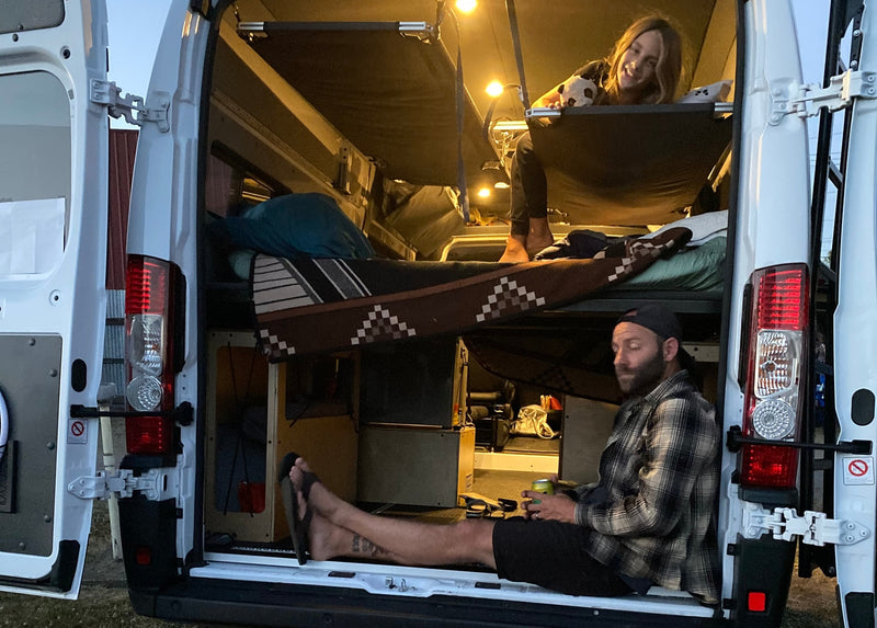 Enjoying a cozy **rv rental** campervan, a man relaxes below while a woman smiles from her bunk. Perfect for van life adventures! — photo 7