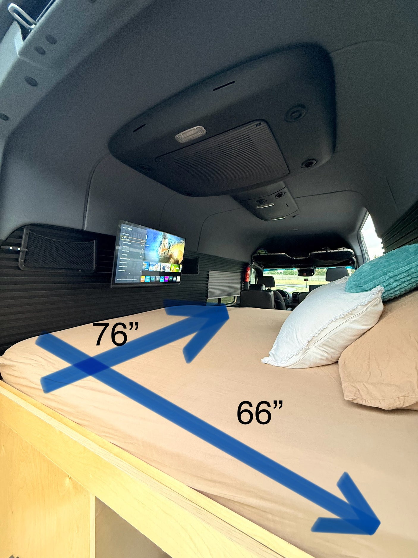 Inside this RV rental, a cozy 76"x66" bed with pillows and a wall-mounted TV provides comfort for your mobile adventure.