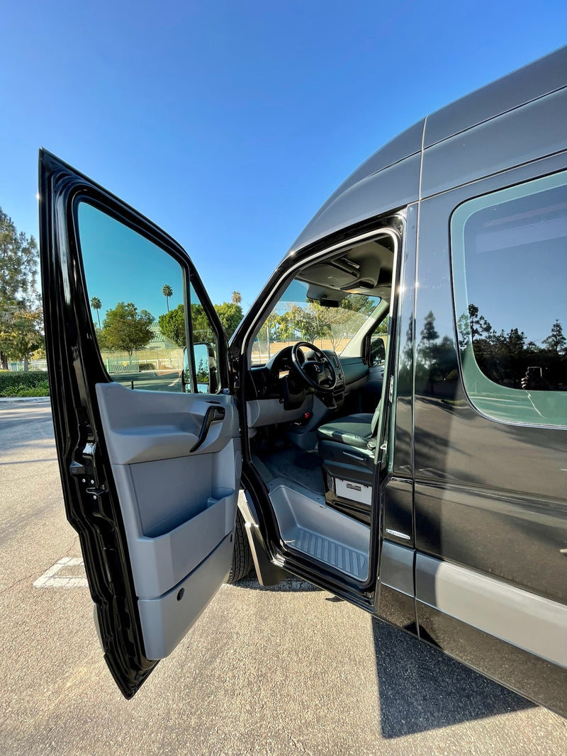 Black Mercedes Sprinter RV rental. Driver's door open, showing steering wheel, dash, & sunny sky. Your travel awaits! — photo 13