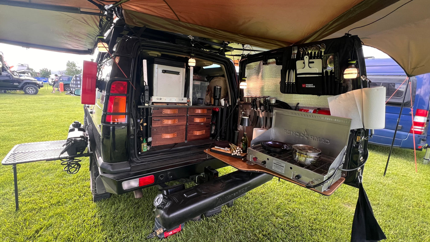 This RV rental showcases an ultimate overlanding kitchen: fridge, stove, pull-out drawers, and outdoor prep table.