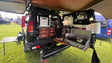 This RV rental showcases an ultimate overlanding kitchen: fridge, stove, pull-out drawers, and outdoor prep table.