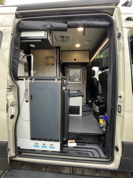 Explore this modern camper van's interior for your next RV rental, featuring a compact kitchen, living area, and bright lighting.