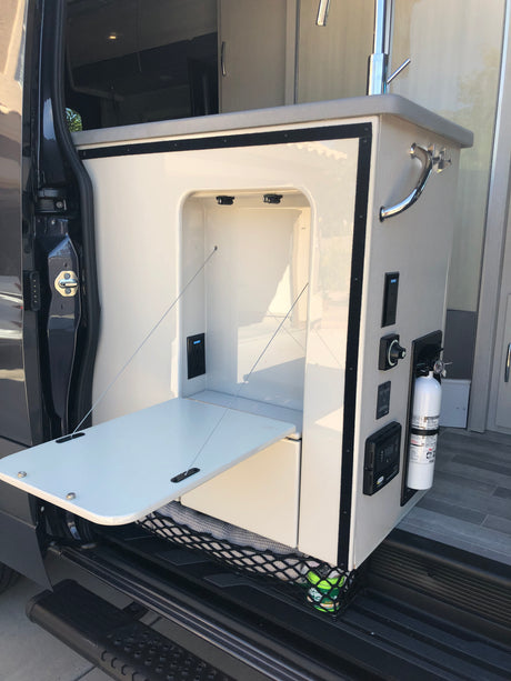 RV rental: Camper van's versatile modular cabinet, offering a fold-down table, power outlets, and a fire extinguisher.
