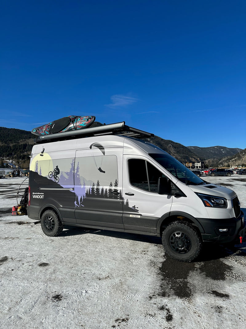  features a vivid outdoor sports wrap & rooftop kayak.|White Ford Transit RV rental with custom graphics & off-road gear — photo 8