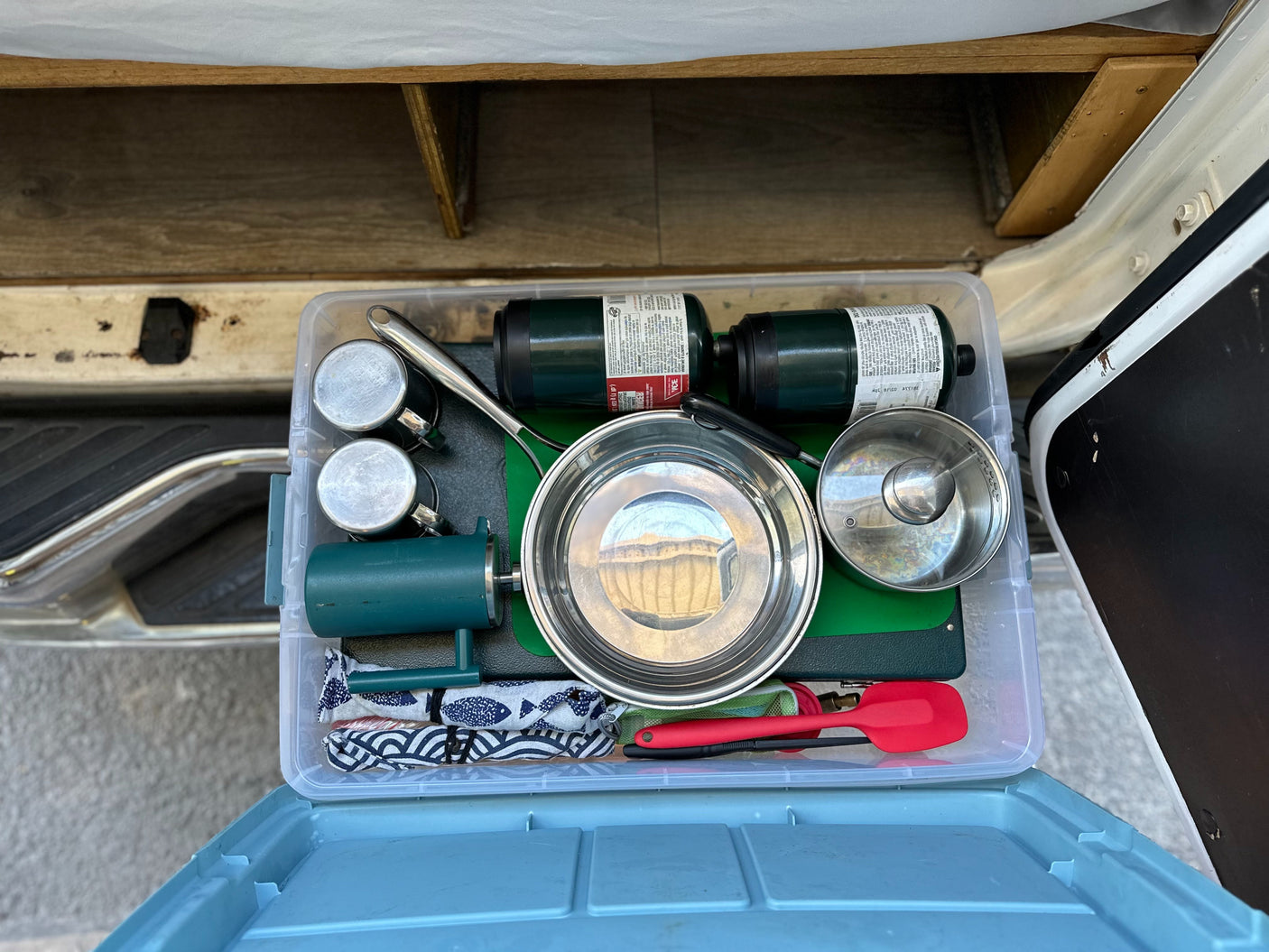 Organized RV rental kitchen bin: propane, stainless pots & mugs, plus cooking utensils for your camping adventure.
