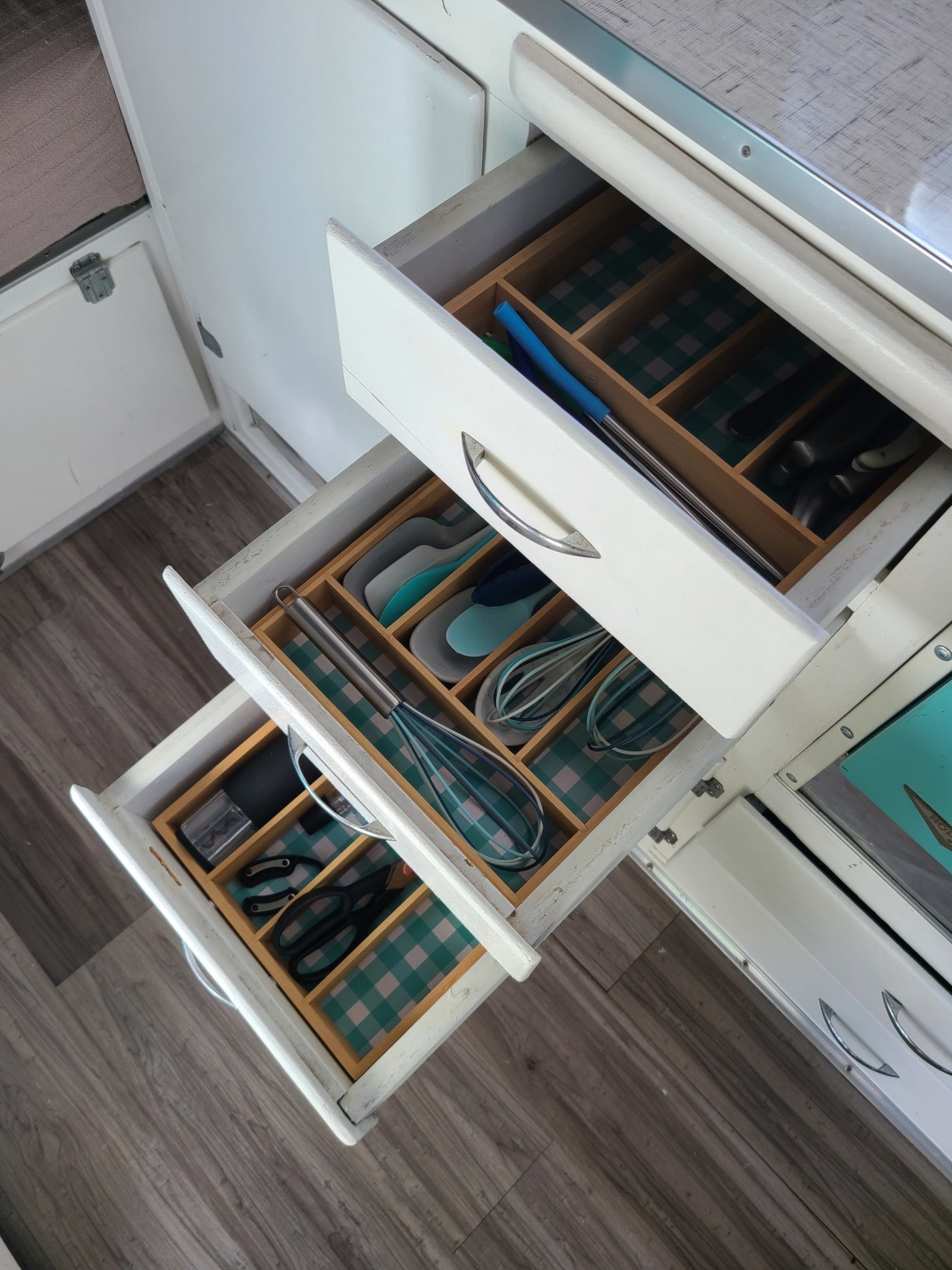 Three organized kitchen drawers with checkered liners and utensils in an RV rental. — photo 3
