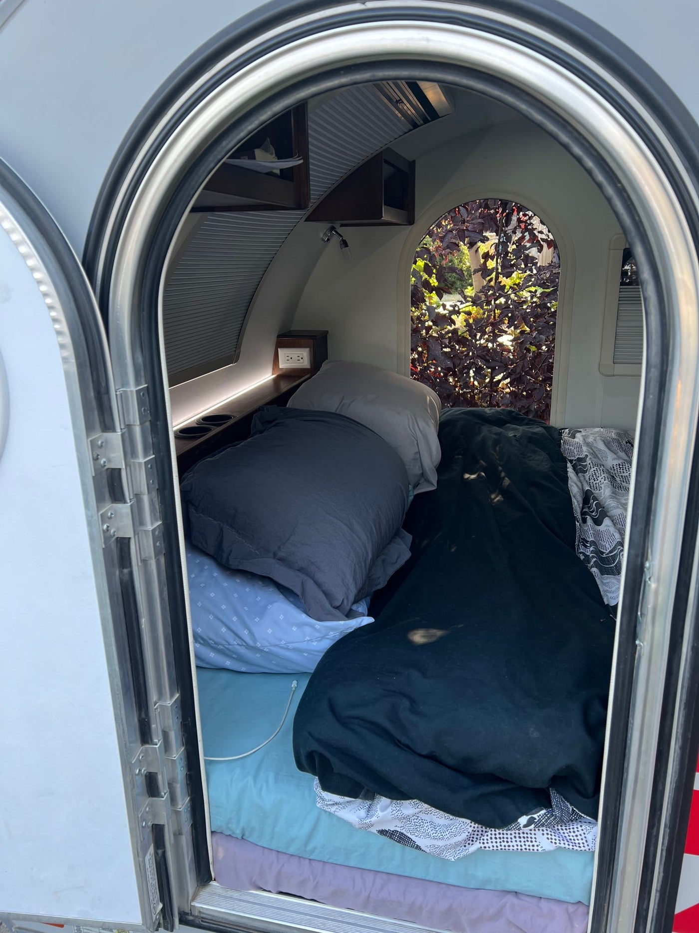  and a pull-out fridge on a slide.|This RV rental's compact sleeping area features a bed with patterned bedding — photo 3