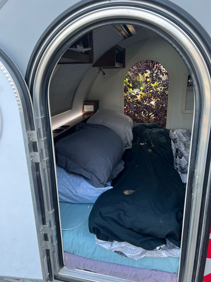  and a pull-out fridge on a slide.|This RV rental's compact sleeping area features a bed with patterned bedding — photo 3