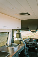 Experience an RV rental! This modern camper van features a full kitchen with stove, sink, wood counters, and driver's area.