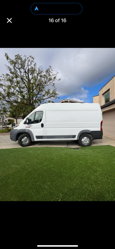 White cargo van, often used for rv rental or deliveries, parked on a driveway next to artificial grass.