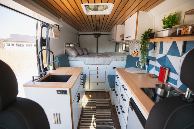 Spacious rv rental camper van interior: modern kitchen, raised bed, and open door view. Perfect for comfortable van life.