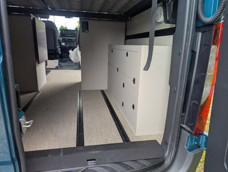 RV rental: Spacious camper van interior with modular cabinets, comfy carpet, and track flooring system.