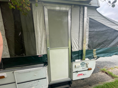 A Coleman pop-up camper RV rental, with canvas walls and entrance door, stands ready for a memorable camping trip.