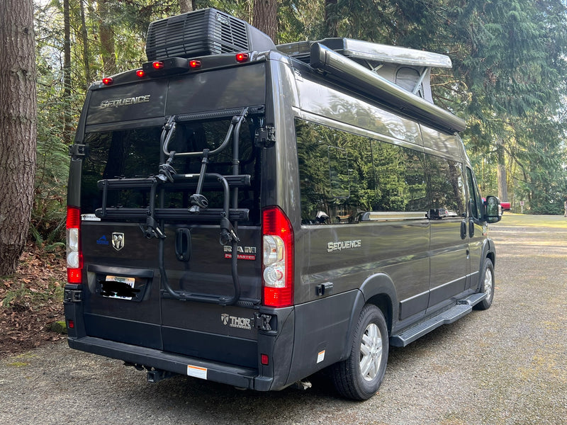 Dark gray Thor Sequence van RV rental, a compact motorhome with a bike rack, parked in a scenic outdoor setting. — photo 16